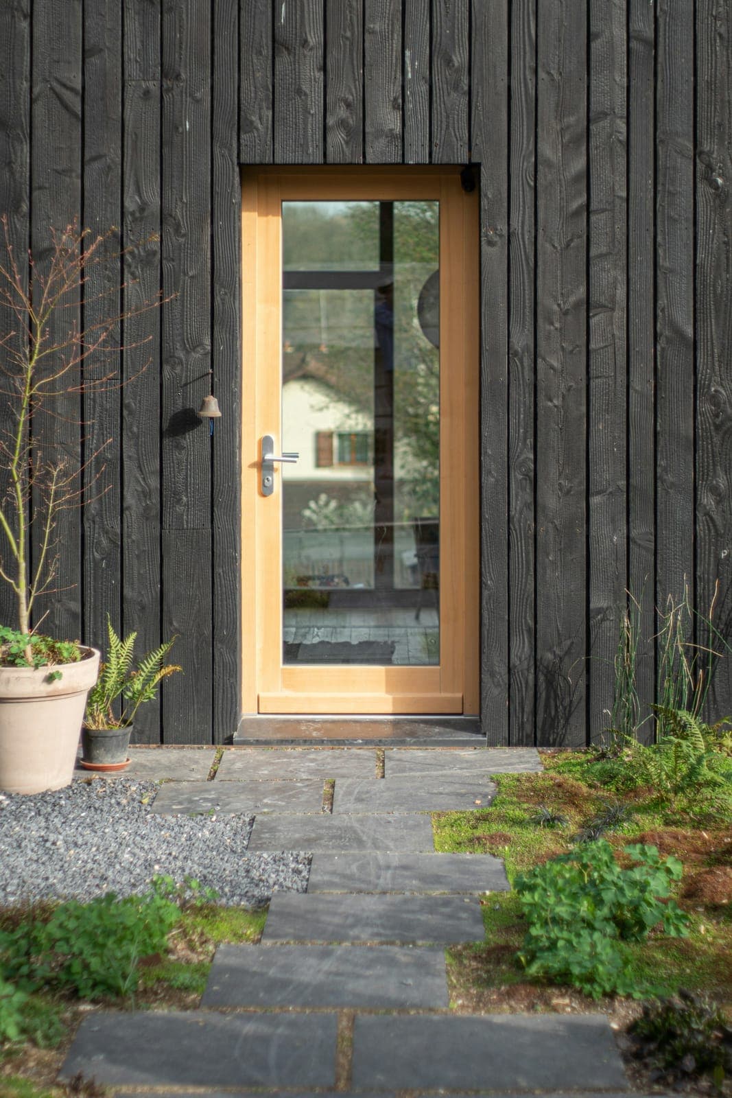 Warm wood-framed glass entrance door on a dark modern home